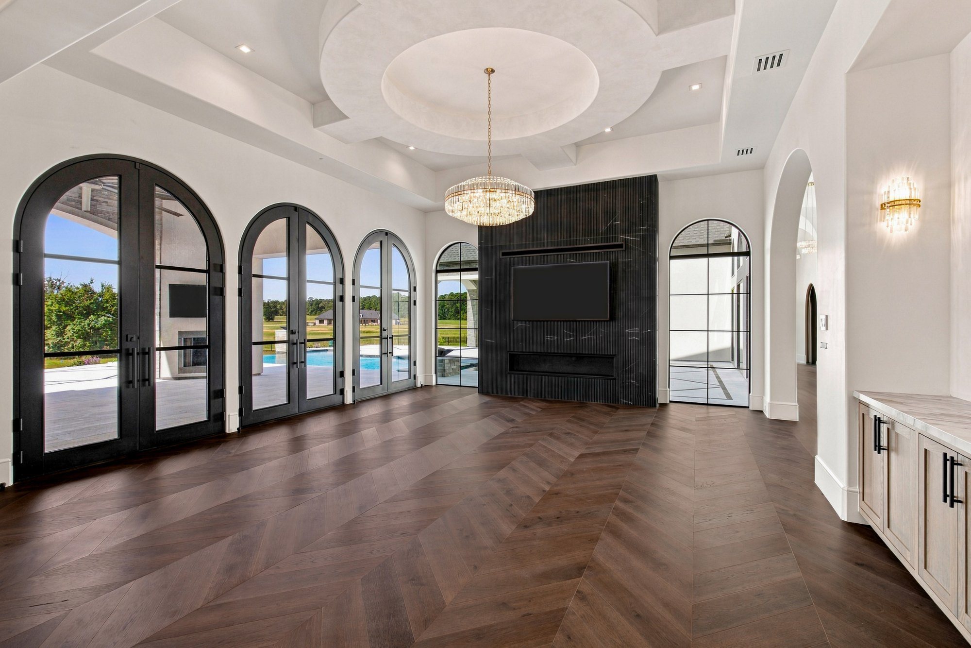 Living room with arched steel windows and chevron wood floors